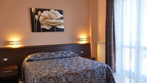 Un dormitorio con una cama grande, dos mesitas de noche, una obra de arte en la pared y un ventanal con cortinas.