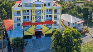 A multi-story hotel with a central staircase, balconies, and a red-roofed entrance.