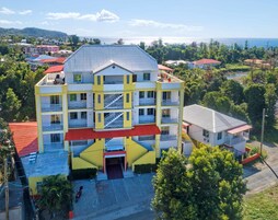 Un hotel de varios pisos con una escalera central, balcones y una entrada con techo rojo.