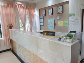 Una mesa de recepción con un reloj, un calendario y un letrero que indica horarios de entrada y salida.