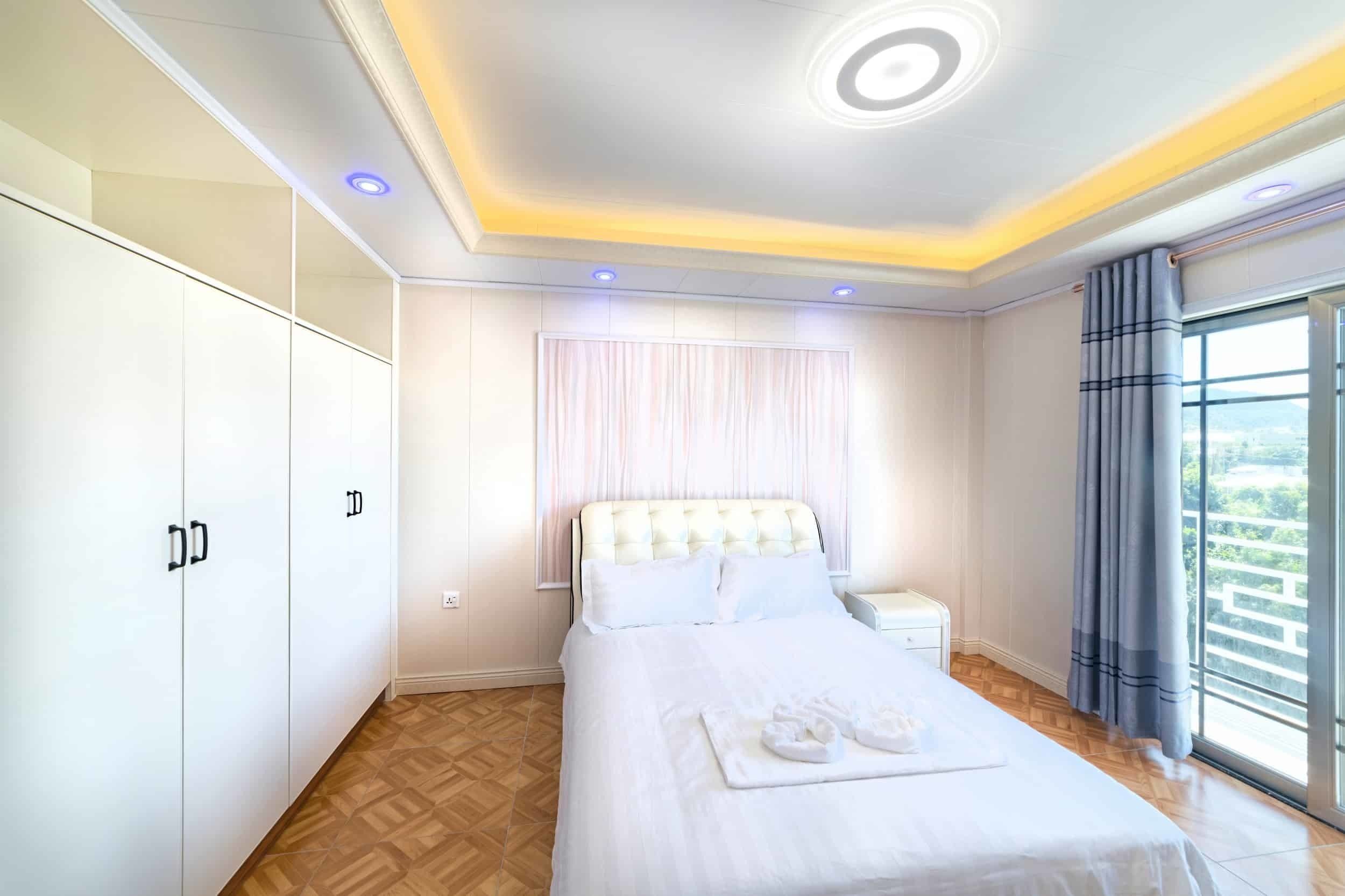 Ein Hotelzimmer mit Bett, Schrank, Nachttisch und einem Fenster mit Vorhängen.