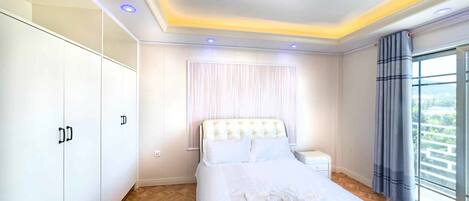 Ein Hotelzimmer mit Bett, Schrank, Nachttisch und einem Fenster mit Vorhängen.