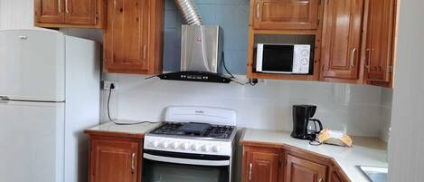 A kitchen with wooden cabinets, a stove, a microwave, and a refrigerator.