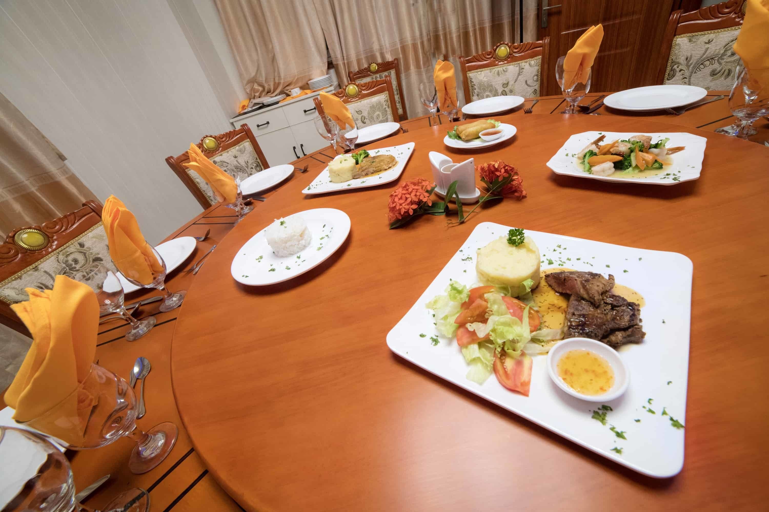 A round dining table set for a meal with plates of food, glasses, and cutlery.