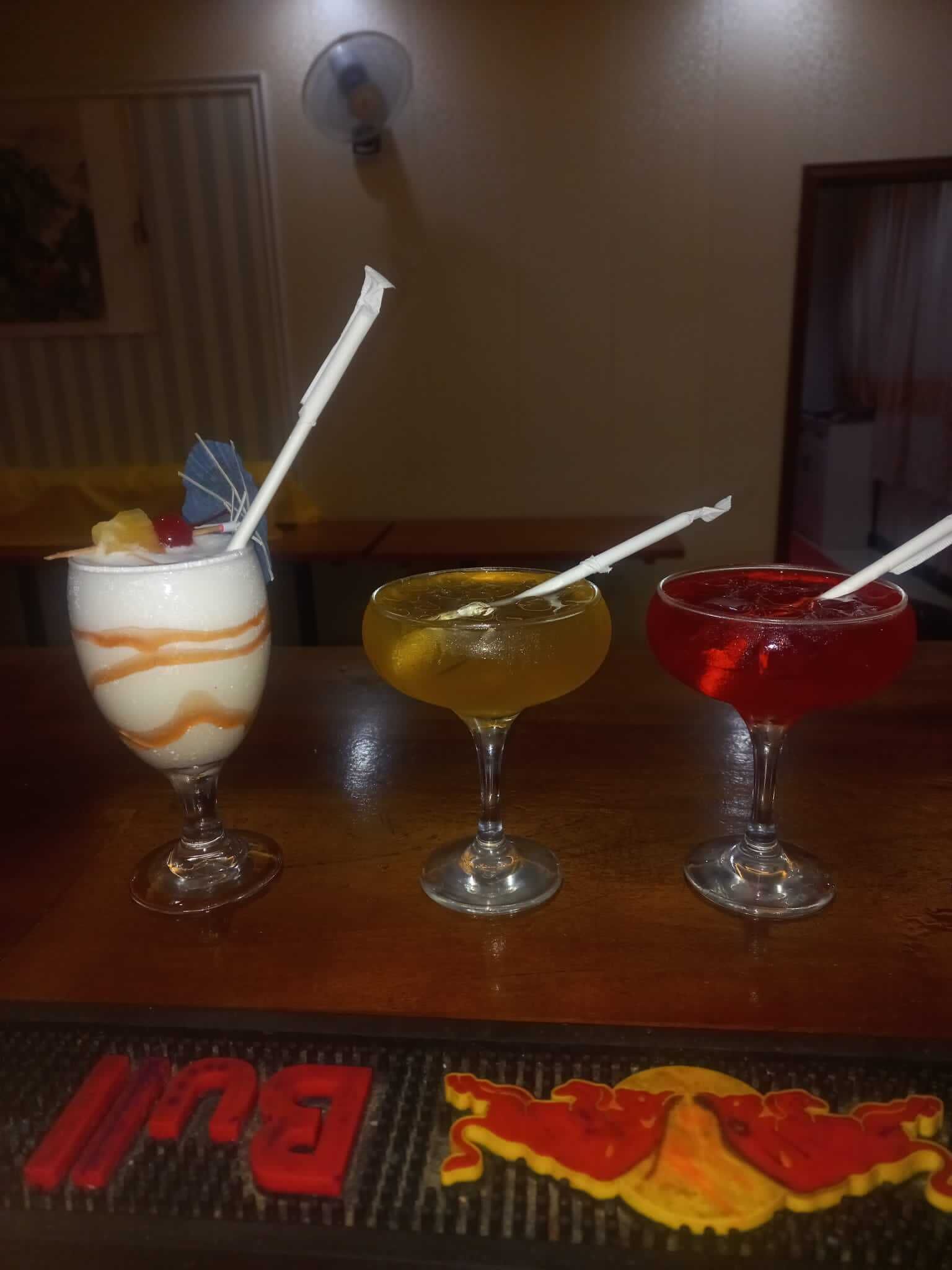 Trois verres posés sur le comptoir d’un bar, accompagnés d’un dessous de verre orné d’un motif représentant un lion.