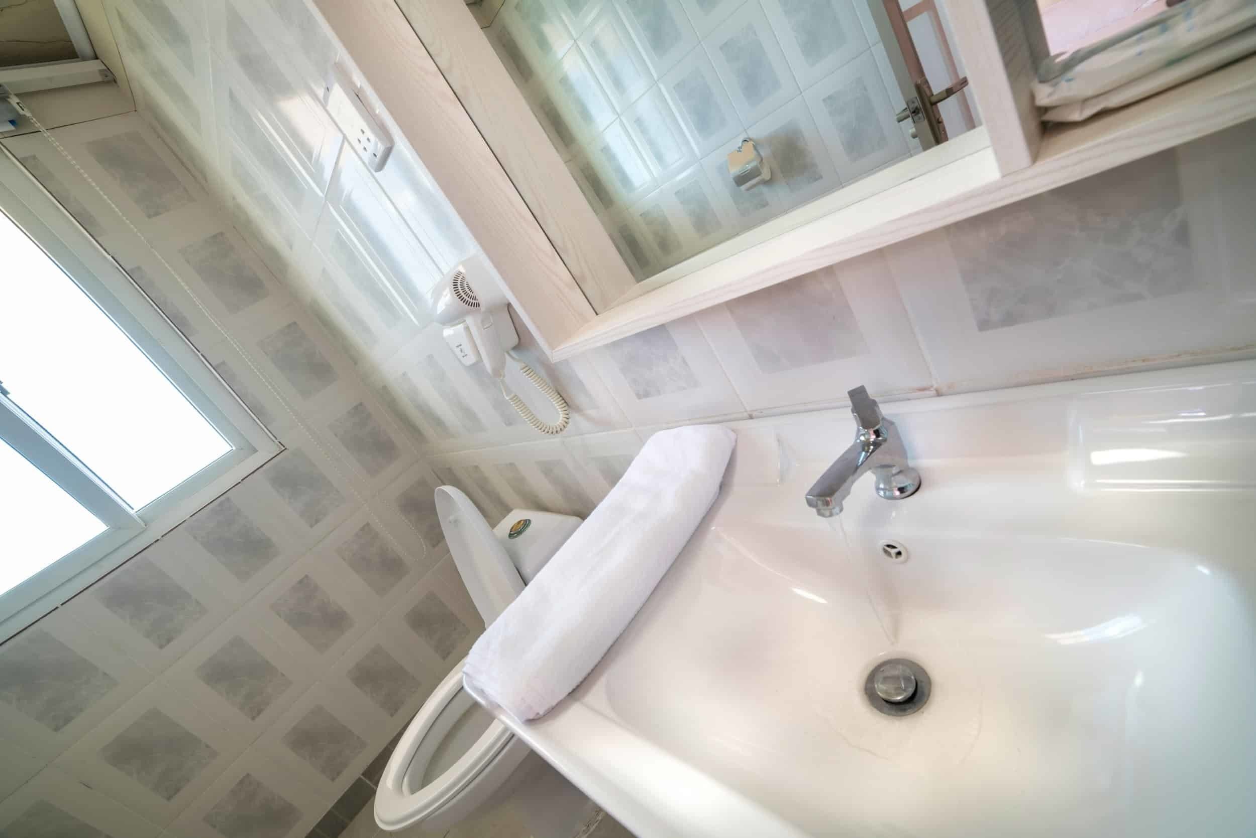 Un baño con un lavamanos blanco, un inodoro y una ventana.