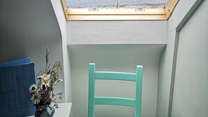 Una habitación con tragaluz, una silla, una mesa y un radiador.
