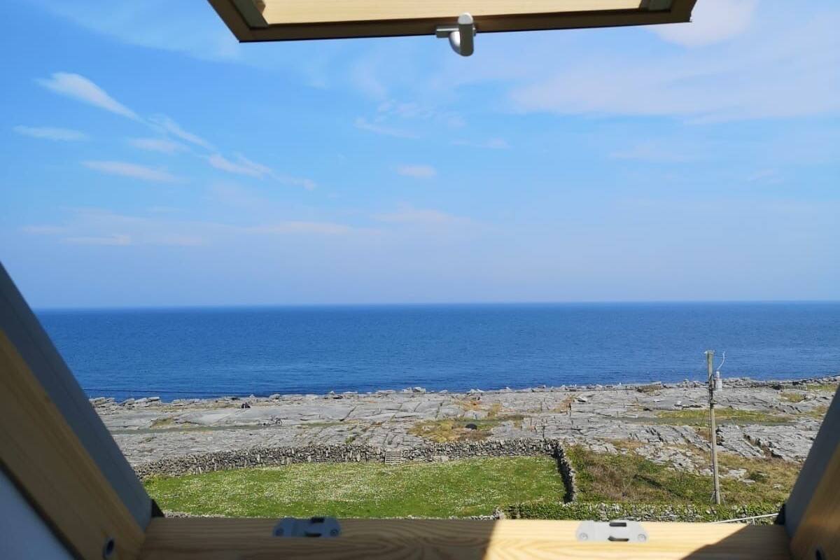A skylight with a view of the ocean and rocky shore.