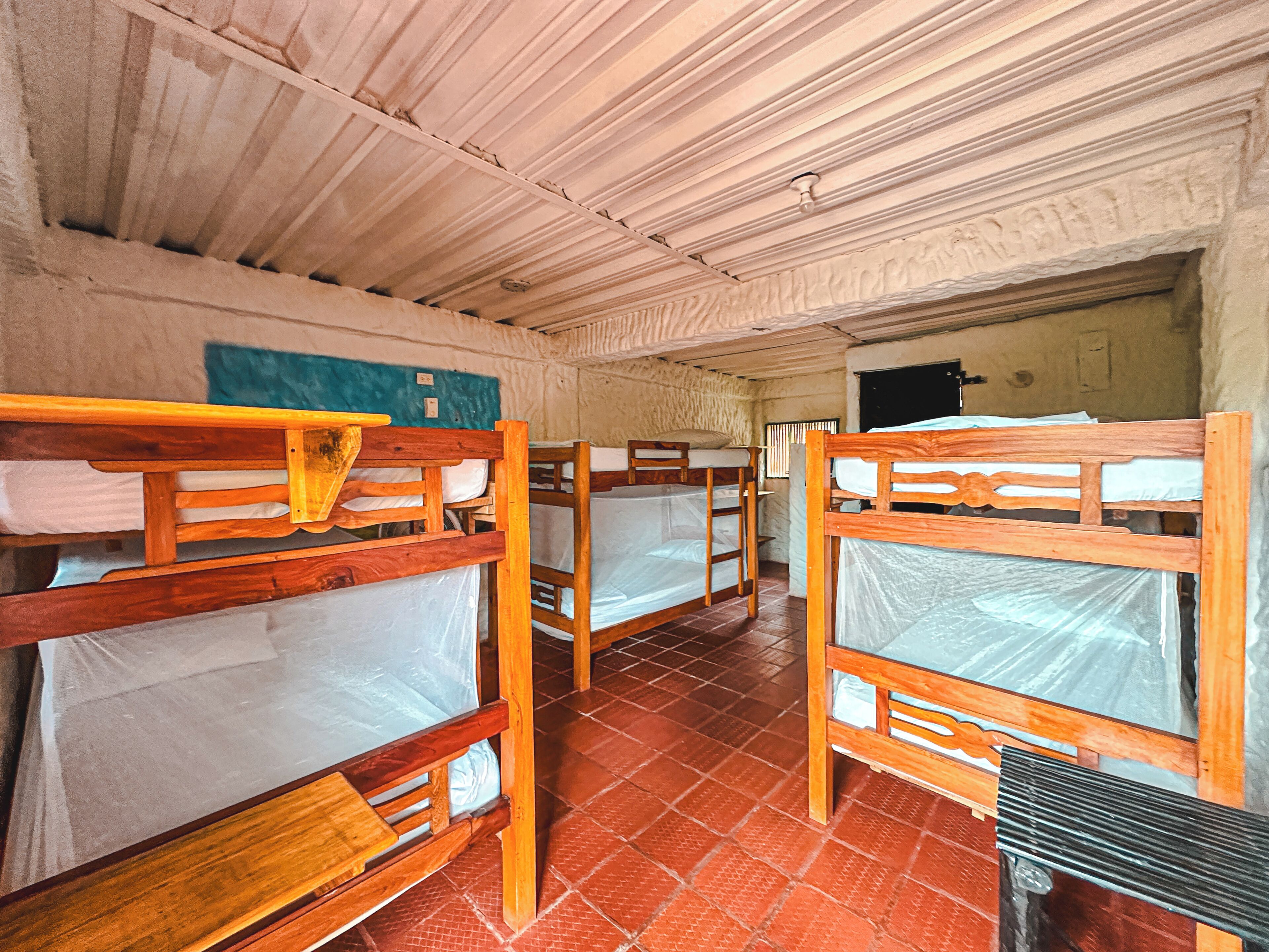 A dormitory room with bunk beds, a tiled floor, and a wall-mounted light fixture.