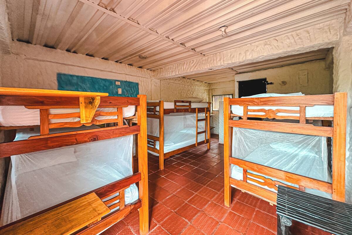 A dormitory room with bunk beds, a tiled floor, and a wall-mounted light fixture.