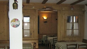 A rustic dining area with wooden walls and tables covered with checkered tablecloths. - La Vecchia Latteria (Pontebba)