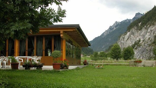 A lodge with a wooden exterior, large windows, and a grassy yard. - La Vecchia Latteria (Pontebba)