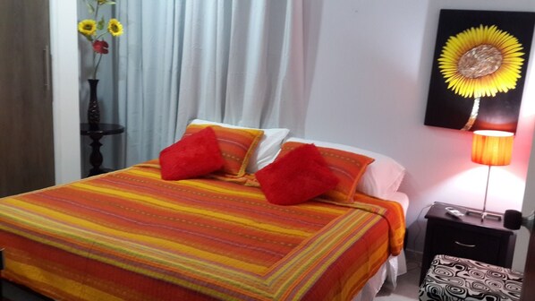 A hotel room with a bed, pillows, a nightstand, a lamp, and a painting on the wall.