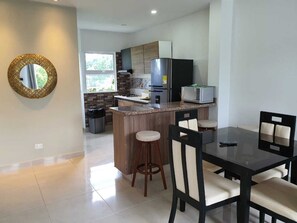 A modern kitchen with a central island, a dining area with a black table and chairs, and a large mirror on the wall. - Caribbean Sea Breeze (San Andrés)