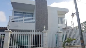 A modern two-story building with a white facade, large windows, and a gated entrance. - Caribbean Sea Breeze (San Andrés)