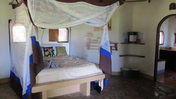Une chambre avec un lit sous un dais, une petite fenêtre et une étagère avec quelques objets.