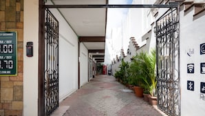 Une ruelle étroite avec un chemin pavé, des portails en métal et des plantes en pot.