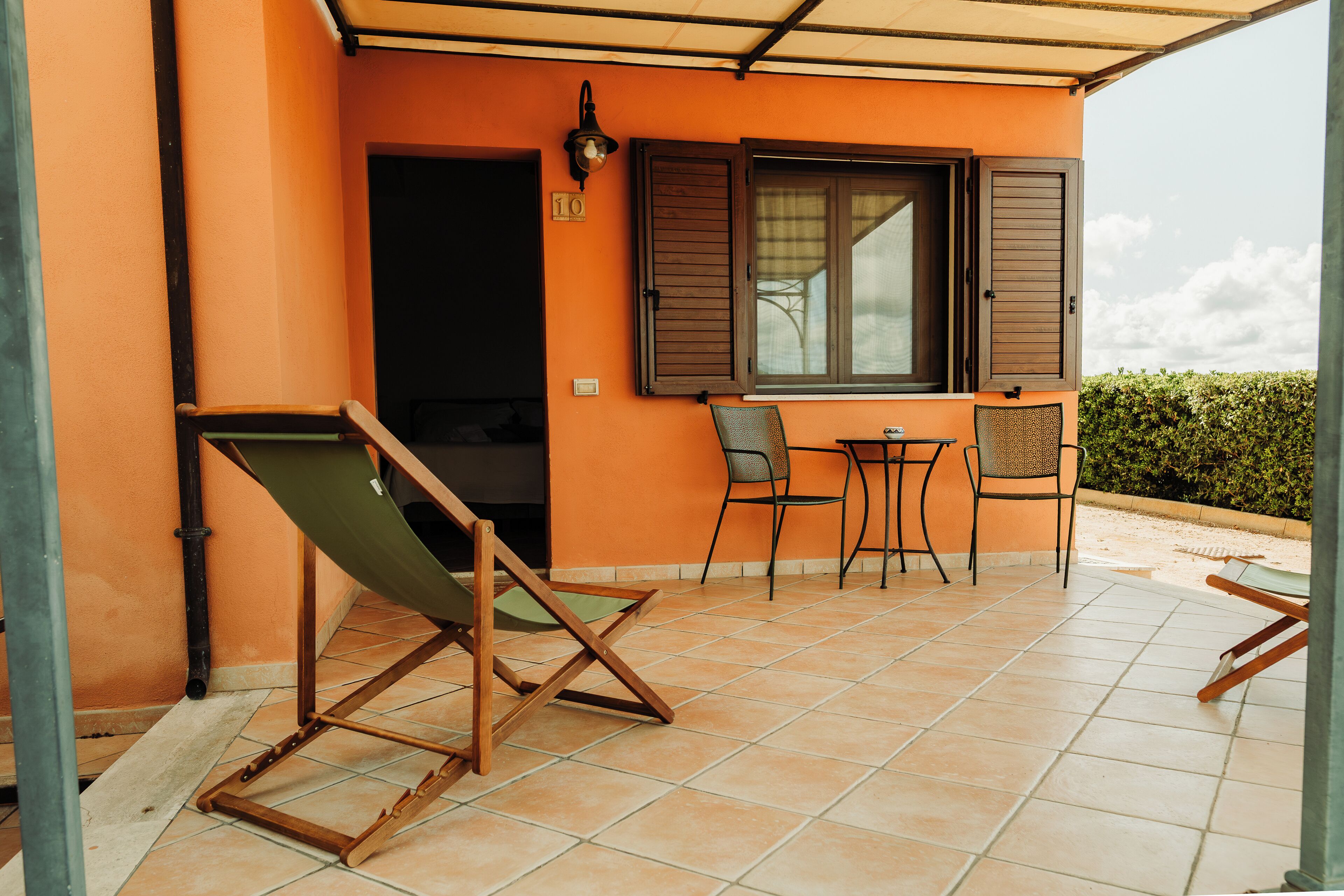Une terrasse avec une chaise pliante verte, une petite table et deux chaises.
