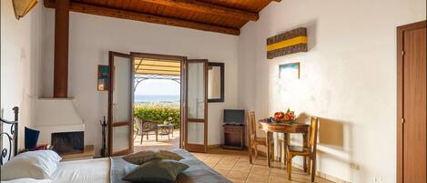 Un dormitorio con cama, escritorio y vista al mar.