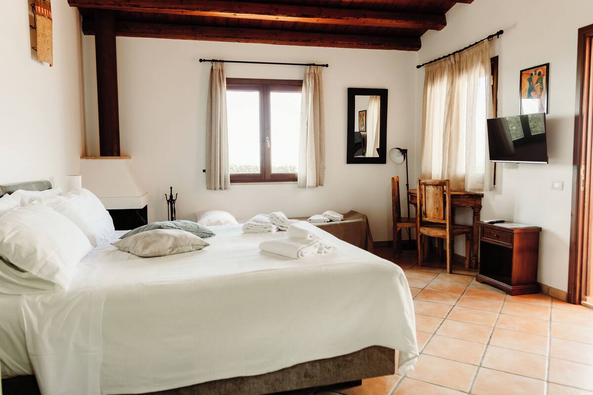 A hotel room with a bed, a desk, a chair, a television, and a window with curtains.