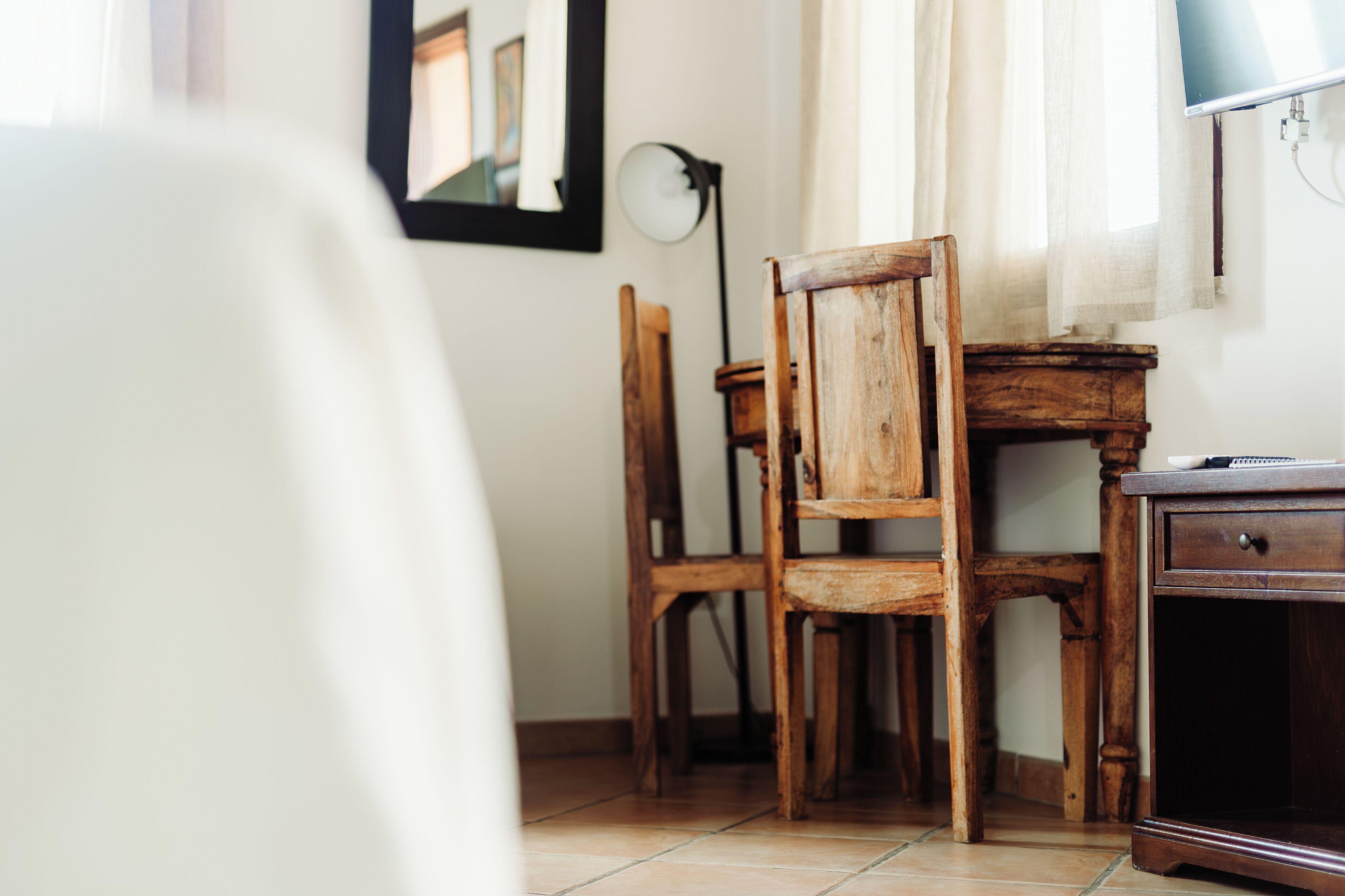 Un bureau en bois, une chaise, une lampe et un miroir accroché au mur.