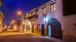 A narrow street with buildings on either side, featuring balconies and large doors. - Hospedaje el Mirador (Villa de Leyva)