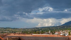 A town with terracotta-roofed buildings, a mountain in the background, and a cloudy sky. - Hospedaje el Mirador (Villa de Leyva)