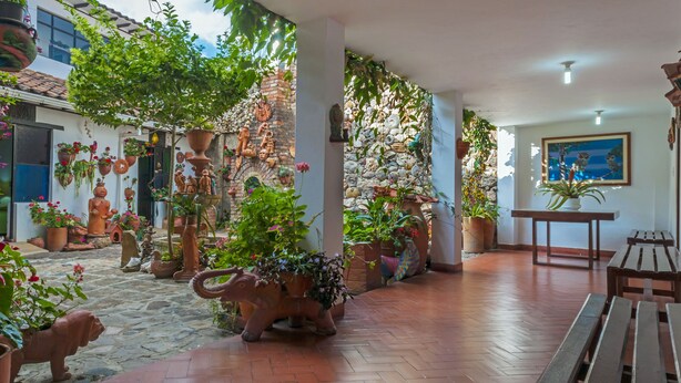 A courtyard with terracotta pots, sculptures, and potted plants. - Hospedaje el Mirador (Villa de Leyva)