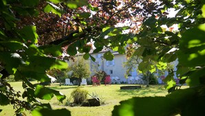 A courtyard with outdoor seating and a building in the background. - Aux Chambres des Bujours (Saint-Georges-des-Coteaux)