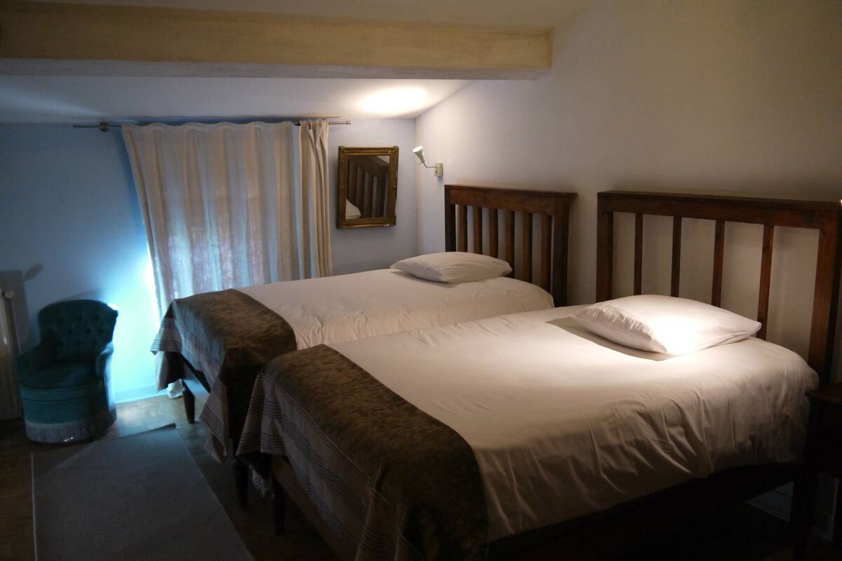 A room with two single beds, a chair, and a small table.