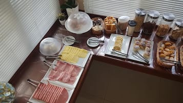 Buffet com diversos alimentos, incluindo carnes, doces e acompanhamentos.