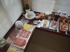 A buffet with various food items including meats, pastries, and condiments. - Hotel Portal das Águas (Jaguariuna)