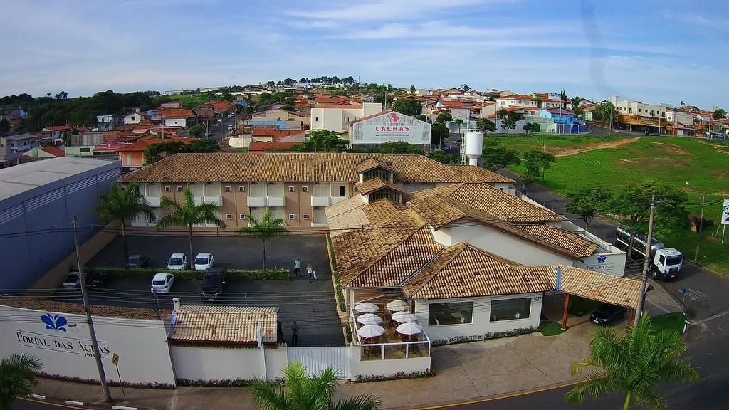 Um edifício com telhado em telhas, estacionamento e uma placa com a inscrição 'Portal das Aguias'.