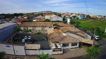 Um edifício com telhado em telhas, estacionamento e uma placa com a inscrição 'Portal das Aguias'.
