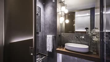 A modern bathroom with a large sink, a towel rack, and a mirror.