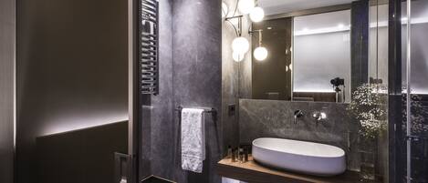 A modern bathroom with a large sink, a towel rack, and a mirror.