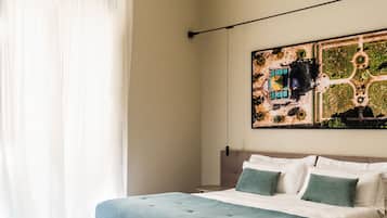 A bedroom with a bed, a green ottoman, and a wall-mounted artwork.