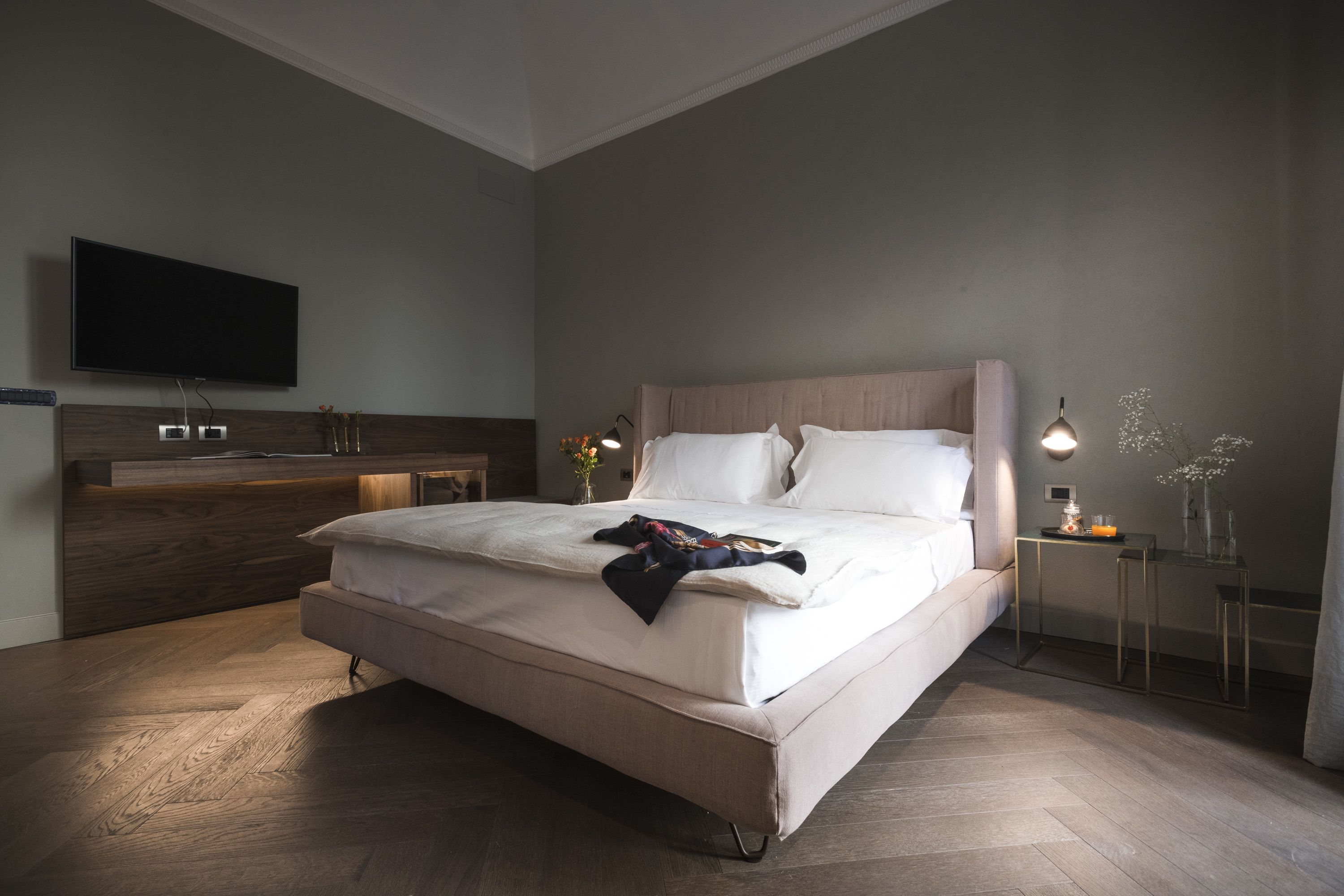 Un dormitorio moderno con una cama grande, mesitas de noche, un televisor de pantalla plana y un cabecero de madera.