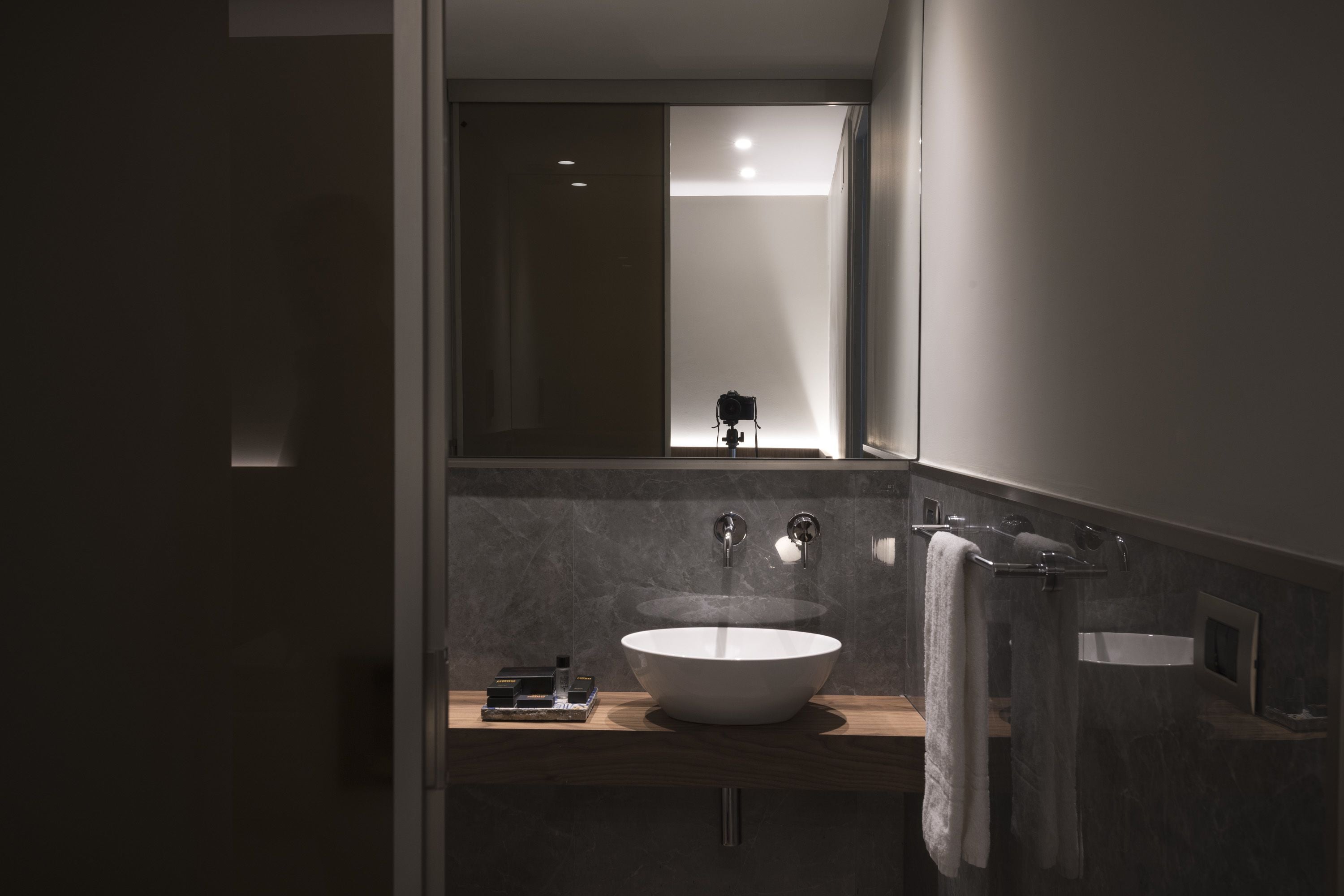 A modern bathroom with a large white sink, a mirror, and a towel rack.