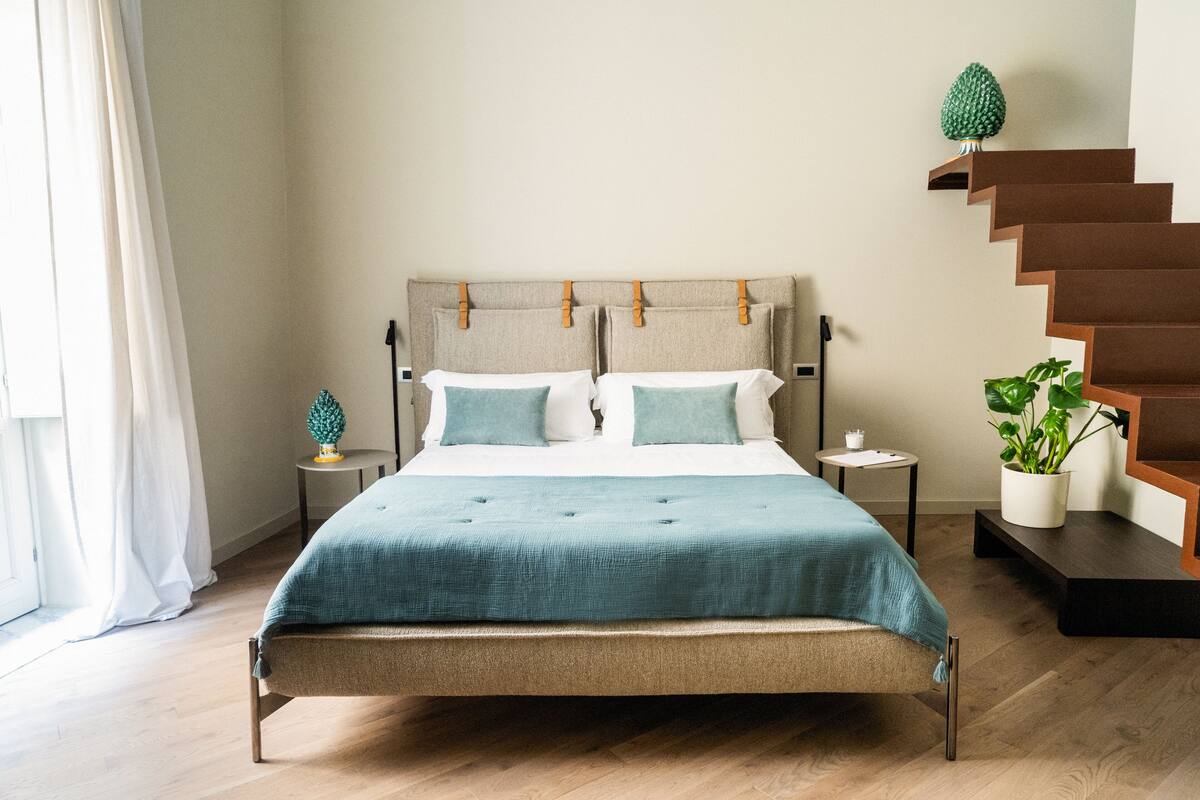 Une chambre à coucher moderne avec un lit, un escalier en bois et une plante en pot.