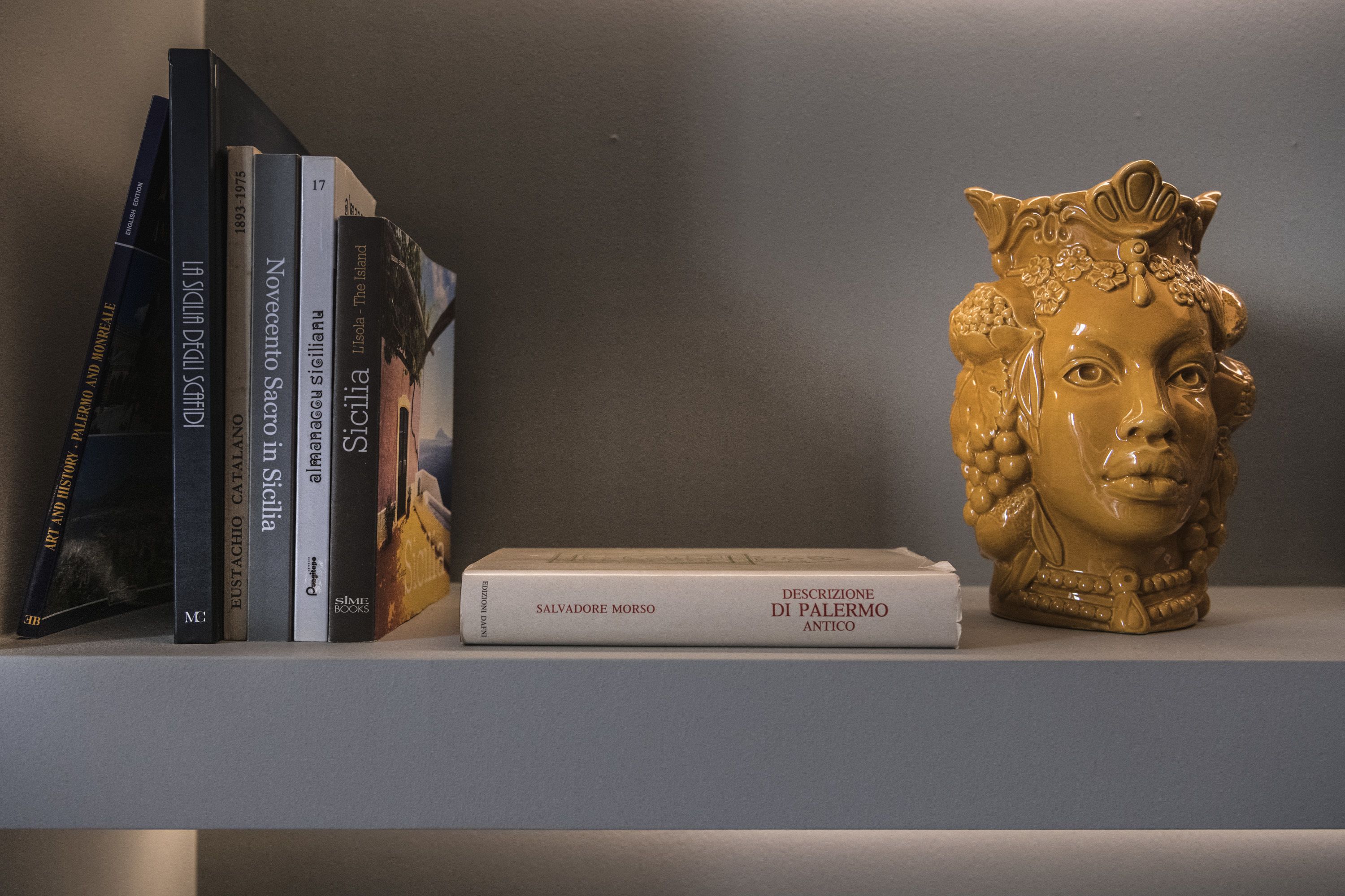 A bookshelf with books and a decorative ceramic bust.