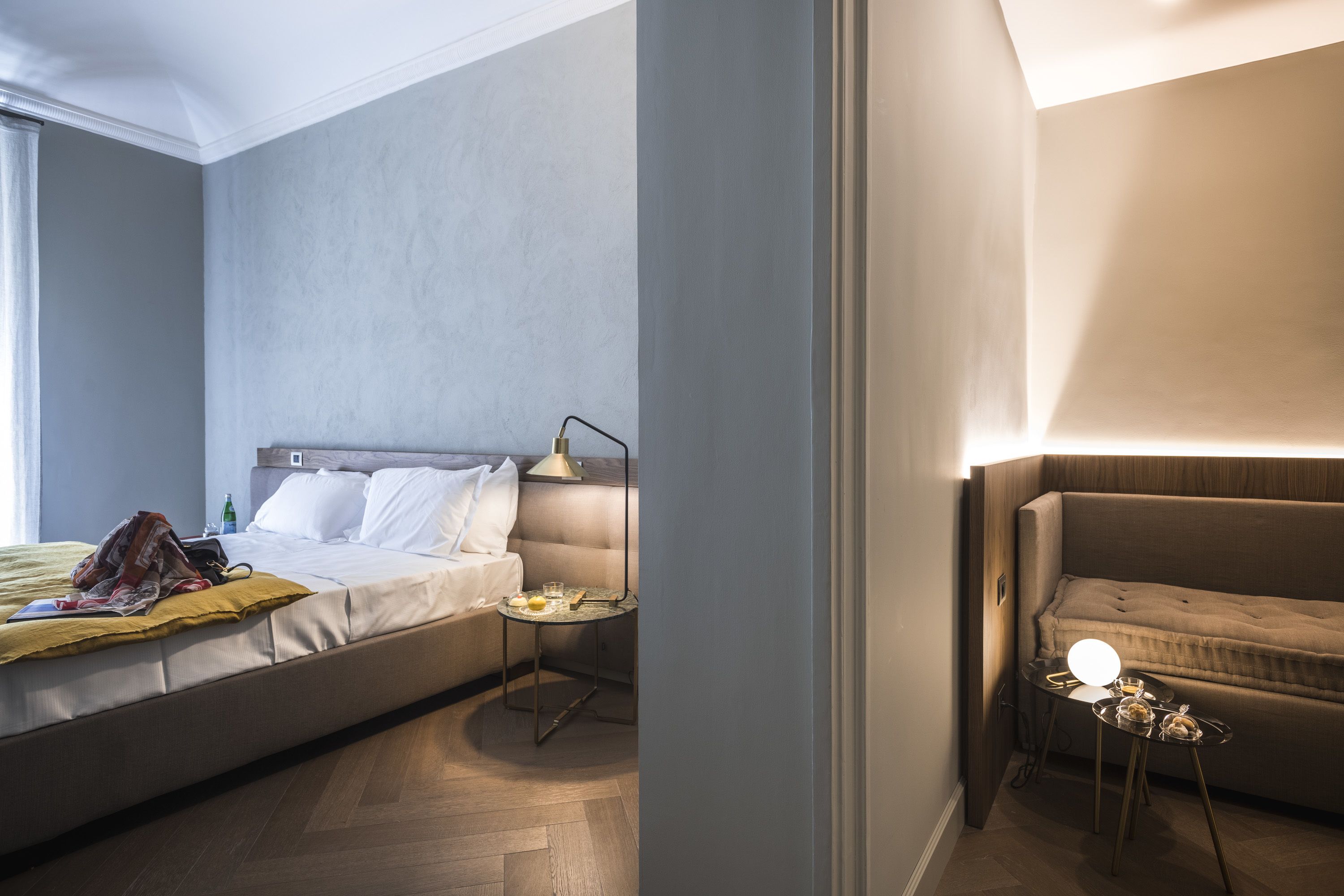 Una habitación de hotel moderna con una cama grande, una mesita de noche con lámpara y una pequeña mesa con lámpara.