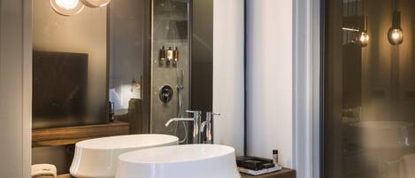 A modern bathroom with two sinks, a large mirror, and a glass shower enclosure.