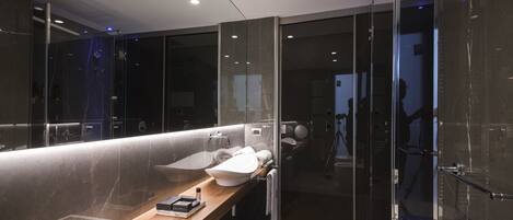 A modern bathroom with a glass-enclosed shower, a wooden vanity, and a large mirror.