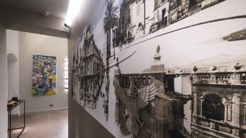 Um corredor com um grande mural de uma cena histórica, uma pintura abstrata moderna e piso de madeira.
