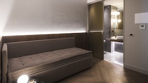 A modern room with a sofa, a mirror, and a bathroom visible through an open door. - inCanto (Palermo)