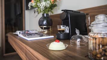 Une table en bois avec une machine à café, un bocal en verre, un livre et un vase rempli de fleurs.