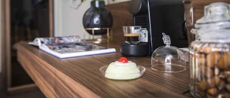 Une table en bois avec une machine à café, un bocal en verre, un livre et un vase rempli de fleurs.