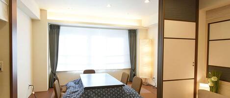 Een hotelkamer met een groot bed, een eettafel met stoelen, een bank en een raam met gordijnen.