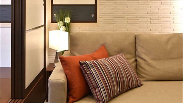 A modern living room with a beige sofa, a striped pillow, and a wall-mounted picture frame.